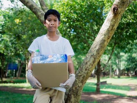 Reduction environmental pollution and recycle concept, Plastic-free, Junk food plastic packaging. Boy hold cardboard boxes for recycling and holding a recycle bin with plastic bottles in the outdoors.