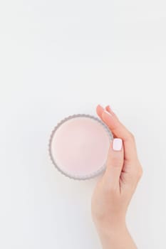 Woman hand with pastel manicure polish holding pink aromatic candle isolated on white background with copy space. Template for feminine beauty blog social media. Spa and wellness concept