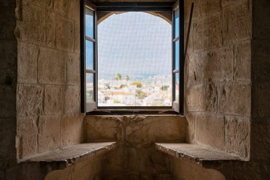 Open window with insect screen showing cityscape view from Kolossi castle interior in Cyprus