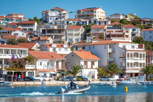Rogoznica, Croatia - October 31, 2022: Tourists are enjoying a sunny day while driving a motorboat in front of the picturesque coastal town of Rogoznica, Croatia