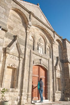 Tourist entering the stone church of Timios Prodromos in Vouni village, on a sunny day with clear blue sky. Limassol District, Cyprus