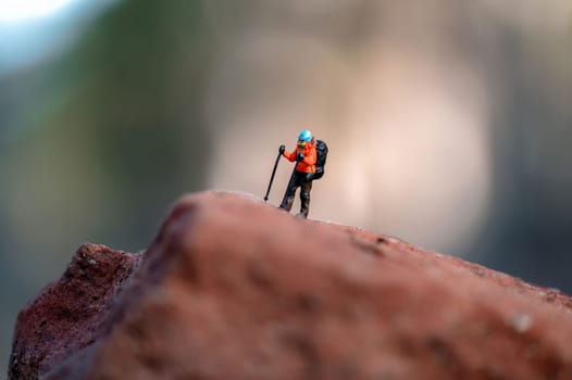 Miniature hiker figurine standing on a rock, enjoying the view from the top