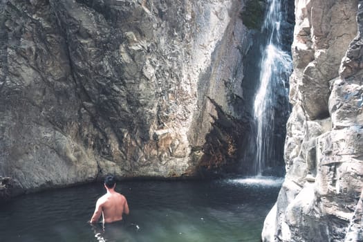 Tourist is taking a refreshing bath at the Millomeris waterfalls in Cyprus