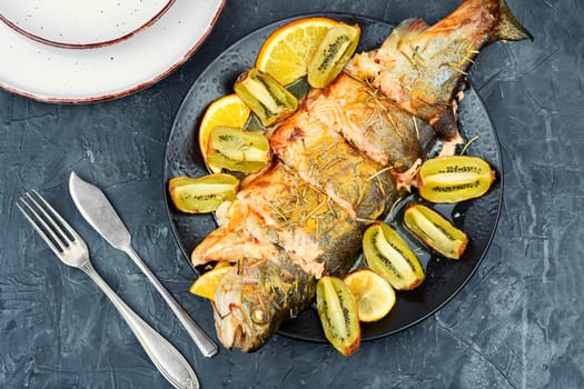 Roasted trout on a plate, baked trout with fruit. Restaurant menu, dieting.