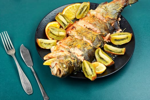 Roasted trout on a plate, baked trout with fruit. Restaurant menu, dieting.