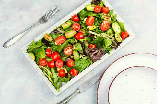 Summer vegan salad with tomatoes, nut and green on a stone tray. Healthy tomatoes salad on a stone plate