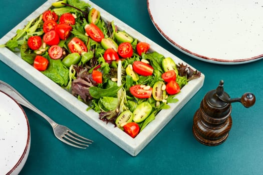 Summer vegan salad with tomatoes, nut and green on a stone tray. Healthy tomatoes salad on a stone plate