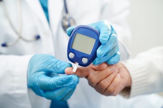 Asian doctor using digital glucose meter for check sample blood sugar level to treatment diabetes.