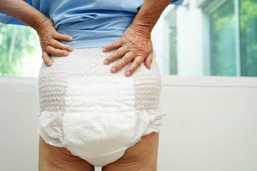 Asian senior woman patient wearing adult incontinence diaper pad in hospital.