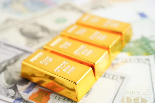 Gold bars on US dollar banknote money, finance trading investment business currency concept.