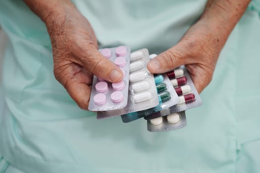 Asian elderly woman holding pill drug in hand, strong healthy medical concept.