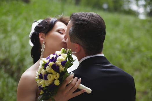 A loving couple is sharing a tender kiss while being surrounded by a breathtakingly beautiful natural backdrop
