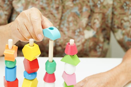 Asian elderly woman playing puzzles game for treatment dementia prevention and Alzheimer disease.