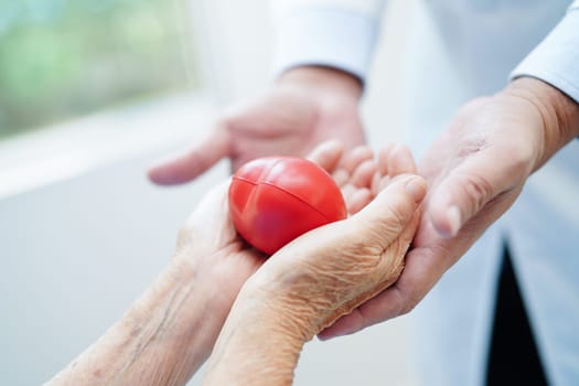 Asian woman doctor holding red heart for health in hospital.