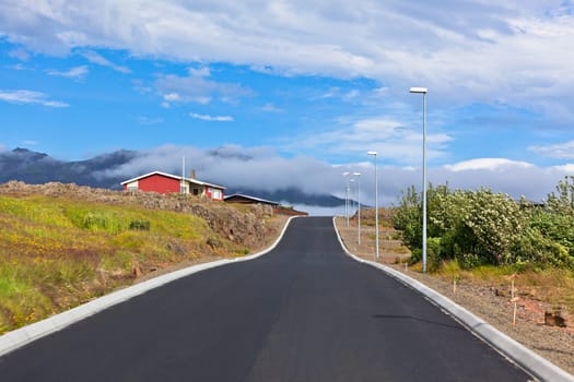 Red Small House and new asphalt road in East Iceland. Horizontal shot