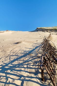 Beautiful calm view of nordic sand dunes and protective fences at Curonian spit, Nida, Klaipeda, Lithuania. Buried wood, desert and sand, sunny blue sky. Sand patterns