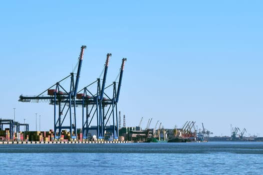 View of port cranes, loading bridges and container terminal. Sea trade, transportation, commerce and cargo