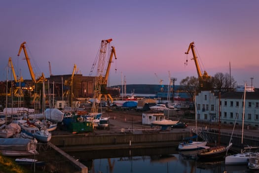 Beautiful sunset port area with portal cranes, yachts and boats in Klaipeda, Lithuania.