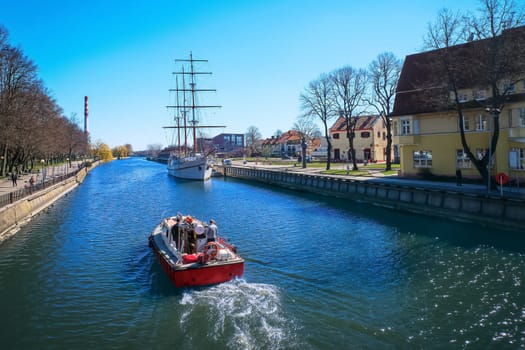 View of Dane river and sailboat or barquentine anchored in old town of Klaipeda, Lithuania.