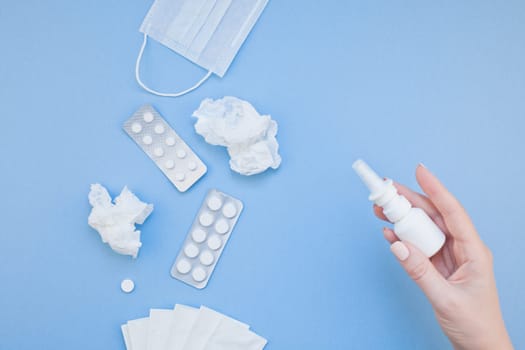 Creative flat lay concept of seasonal spring allergy with napkins, pills, face mask, drops in a bottle and a female hand with copy space background minimal style, template for text