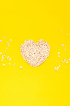 Creative flat lay concept top view of oatmeal flakes for healthy and vegetarian organic food for breakfast on a bright yellow color paper background with copy space in minimal style, template for text