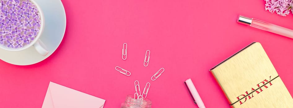 Creative top view flat lay of workspace desk styled design office supplies and cup of tea with copy space on a bright pink color paper long wide banner. Template for feminine blog social media