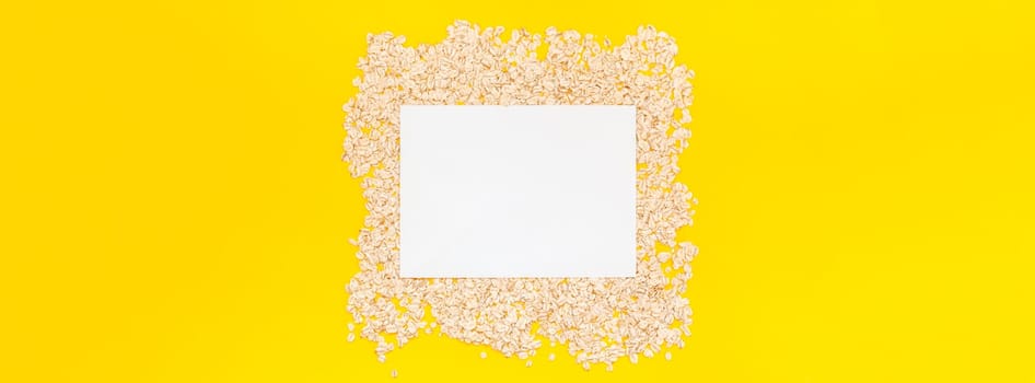 Creative flat lay concept top view of oatmeal flakes for healthy and vegetarian organic food for breakfast on a bright yellow color paper long wide banner with copy space in minimal style
