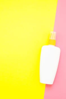Sunscreen blank bottle mockup on bright yellow and pink duotone paper background. Summer vacations creative flat lay concept template for text