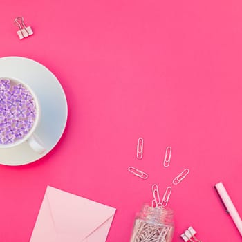 Top view flat lay of workspace desk styled design office supplies and cup of tea with copy space on a bright pink color paper background minimal style. Square Template for feminine blog social media