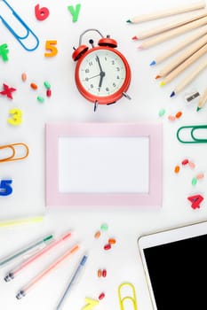 Creative flat lay back to school concept blank tablet with alarm clock, color school and office supplies on white table background with copy space, frame, template for text or design