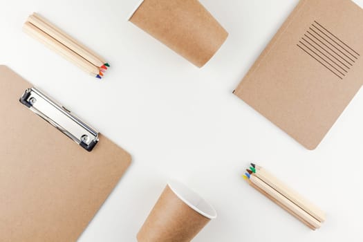 Creative top view flat lay of workspace desk styled recycled brown design office supplies and coffee cups with copy space white table background minimal eco style. Concept of environmental protection