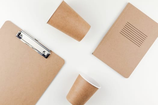 Creative top view flat lay of workspace desk styled recycled brown design office supplies and coffee cups with copy space white table background minimal eco style. Concept of environmental protection