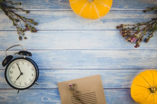 Top view of autumn orange pumpkins and dry flowers and grass in box thanksgiving background over blue toned wooden table with copy space. Template for fall harvest mood text