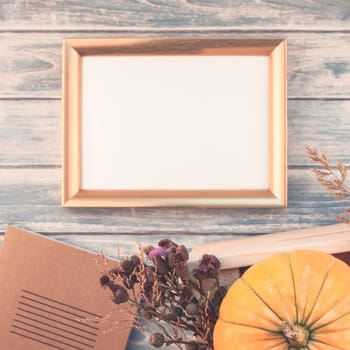 Square Top view of autumn orange pumpkins and dry flowers with grass thanksgiving background over blue toned wooden table with golden frame mock up and copy space in rustic style, template for text