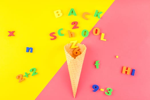 Creative flat lay back to school concept with waffle cone and welcome letters message on bright yellow and pink paper background with copy space, template for text or design