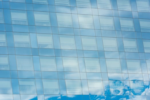 blue sky and clouds reflected in windows of modern office building