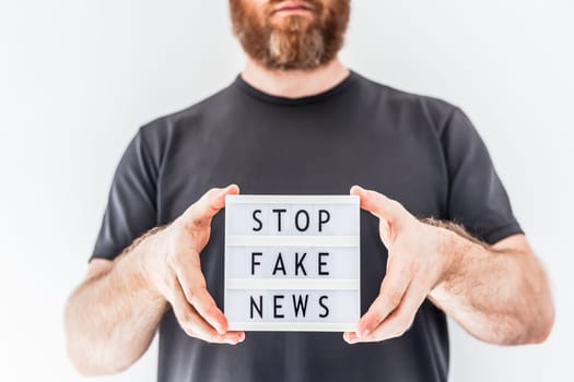 Fake news infodemics during Covid-19 pandemic concept. Man hands holding lightbox with text Stop fake news on foreground. People want to know the truth about coronavirus world spread.