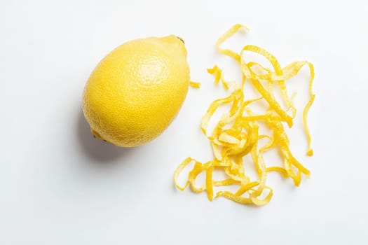 A vibrant whole lemon lies next to finely sliced lemon zest, showcasing the bright yellow color and fresh aroma. This arrangement highlights the fruits culinary potential and zests texture.