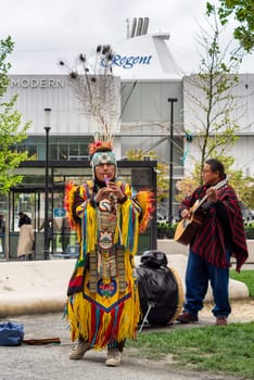 Istanbul, Turkey - May 5, 2023: Two Native Americans musicians wearing colorful traditional costume and busking playing courting flute and guitar in front of Istanbul Modern at Galataport, Karakoy