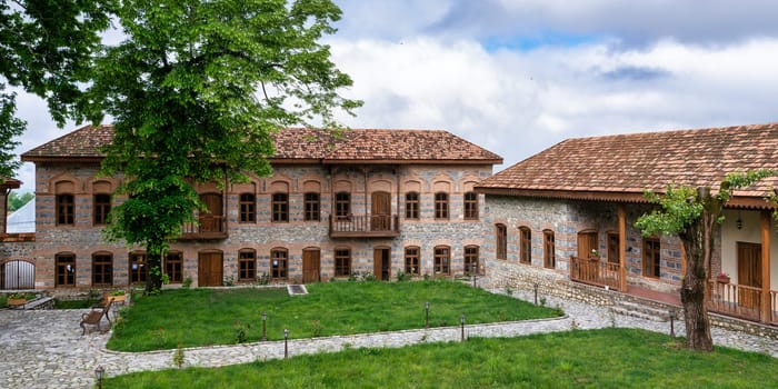 The exterior of the Shaki Khans Mosque Complex, a historic structure in Shaki, Azerbaijan, showcases stone walls, wooden balconies, and traditional architectural elements