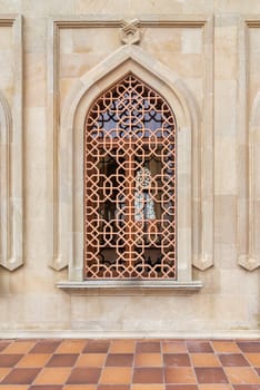 This historic building features an ornate window with intricate lattice work, allowing natural light to filter through while highlighting the craftsmanship of the architecture