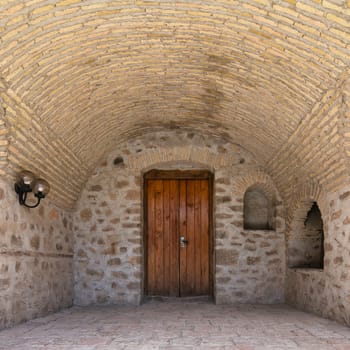The courtyard of the Upper Caravanserai in Shaki, Azerbaijan features stunning stone walls and an arched ceiling, reflecting the region's rich architectural heritage
