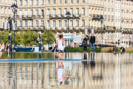 FRANCE, BORDEAUX - SEPTEMBER 20: People having fun in a mirror fountain in front of Place de la Bourse in Bordeaux, France on September 20, 2015
