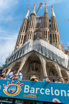 SPAIN, BARCELONA - SEPTEMBER 13: People sitting on a double decker tourist coach in front of The Sagrada Familia Cathedral in Barcelona on September 13, 2015