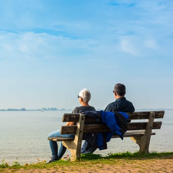 NETHERLANDS, MARKEN - OCTOBER 3: happy romantic middle aged couple enjoying sea view sitting on the bench on October 3, 2015