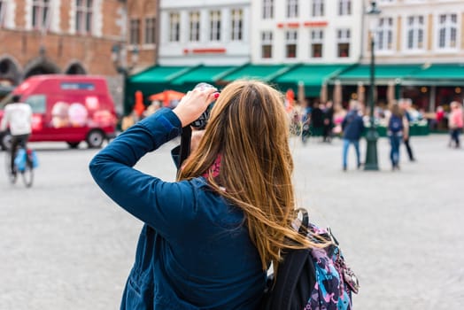 BELGIUM, BRUGES - MAY 22: Woman is taking pictures on the street of Bruges on May 22, 2015
