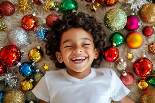 A cheerful child smiles while lying on a cozy surface surrounded by vibrant Christmas ornaments, creating a joyful holiday mood.