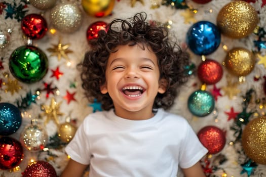 A delighted young child smiles widely while lying on a cozy surface decorated with vibrant Christmas ornaments and stars.