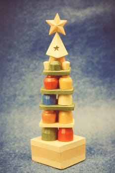 A wooden toy resembling a Christmas tree is stacked with colorful pieces, showcasing creativity for children's interactive playtime.