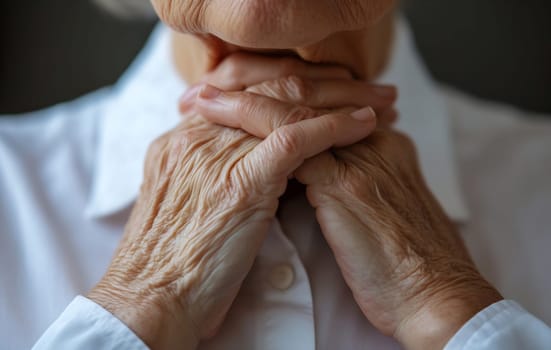 An elderly woman gently clasps her hands, deep in thought while enjoying a serene moment indoors on a peaceful afternoon.
